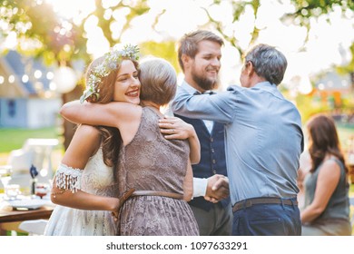 Guests congratulating bride and groom at wedding reception outside in the backyard. - Powered by Shutterstock