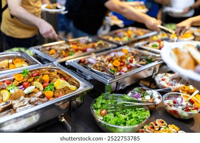 Guests enjoy a vibrant buffet with an array of dishes and fresh salads, mingling at a community event filled with laughter and conversation. - Powered by Shutterstock