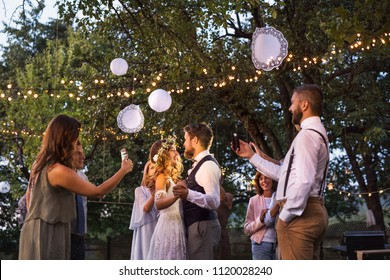 Guests with smartphones taking photo of bride and groom at wedding reception outside. - Powered by Shutterstock