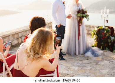 Guests At The Wedding Ceremony Filming The Bride And Groom On The Phones 