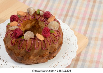 Gugelhupf Marble Bundt Cake, Filled With Dried Blackcurrant And Chestnut Paste, Garnished With Blackcurrant Icing, Marron Glace, Whole Almonds, Freeze-dried Raspberry, Pistachios, And Silver Dragees.