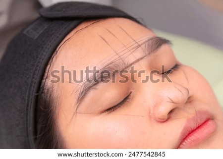 Guide lines made from inked threads to get the desired eyebrow shape for microblading procedure.