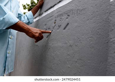 A guide showing and explaining the reason of scratches on the coral rock wall at Male Friday Mosque Complex, Maldives.