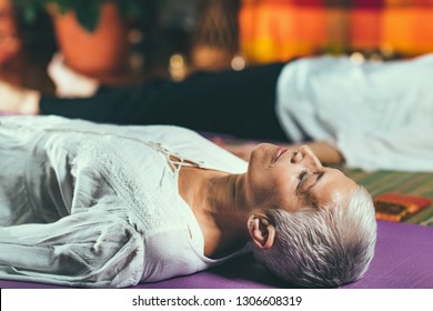 Guided meditation therapy. Senior woman meditating, lying on the floor