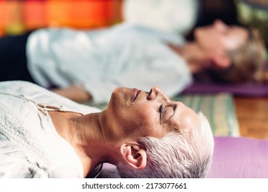 Guided meditation therapy. Senior woman meditating, lying on the floor