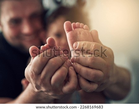 Guiding her footsteps. Closeup shot of a mans hands holding his daughters feet.
