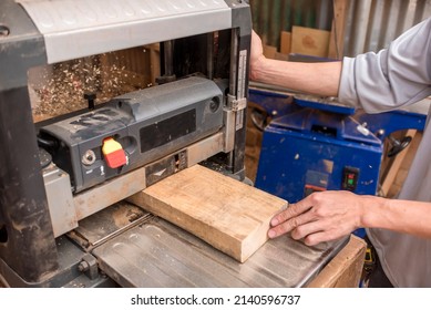 Guiding a plank of wood into a portable thickness planer. A woodworking machine to trim boards to a consistent thickness. At a furniture making shop. - Powered by Shutterstock