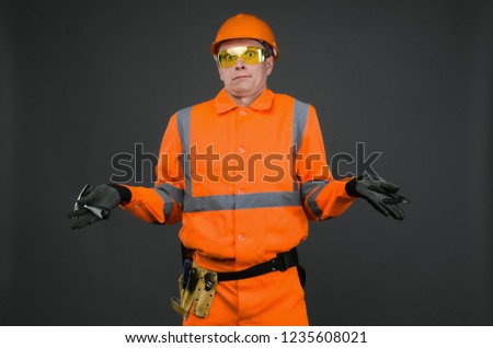 Guilty builder worker justifies about lateness of construction and spreads his hands isolated on blue background. Construction mistake.