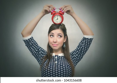 Guilty look woman holding in hands alarm clock and hides her eyes. Latecomer student or emloyee. Be late at work or school. Oversleep concept.