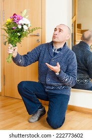 Guilty  Man Kneeling With  Bouquet Of Flowers. 