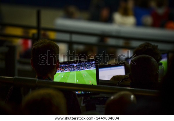 GUIMARAES, PORTUGAL - June 05, 2019: Journalists\
in front of the screens with football in the stadium in the press\
box during the UEFA Nations League match between England and\
Netherlands,\
Portugal