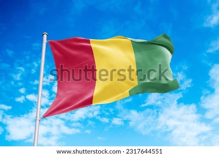 Guinea flag waving in the wind, blue sky background