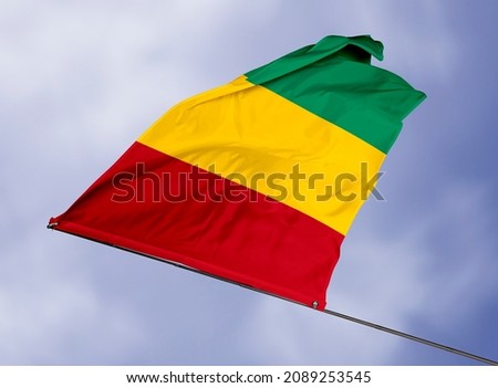 Guinea's flag is isolated on a sky background. flag symbols of Guinea. close up of a Guinean flag waving in the wind.