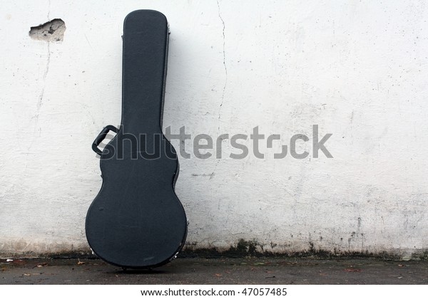 The guitar case rest on a\
wall.