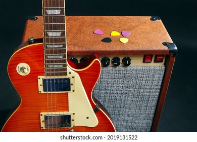 Guitar combo amplifier with honey sunburst guitar on the black background.