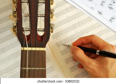 Guitar With Hand Composing Music On Manuscript. For Concepts Like Music Composition And Creativity.