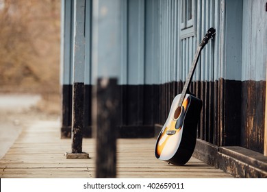 guitar leaning on a old wooden porch