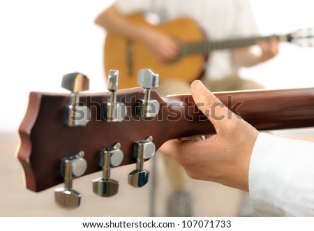 Guitar lesson or two musicians playing together, shot from behind one guitar, with shallow focus