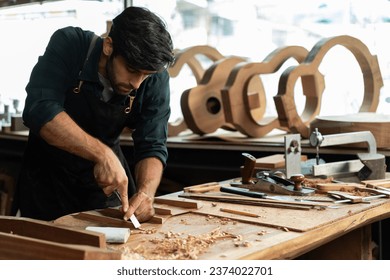 guitar luthier using a chisel to shave the bracing of an acoustic guitar. The luthier is carefully working to ensure that the braces are the correct shape and size - Powered by Shutterstock
