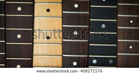 Guitar necks aligned, fretted rosewood, maple and ebony fingerboard necks with round dots for position marker.