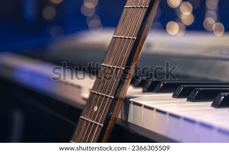 Guitar and piano keys close-up on a blurred background with bokeh.