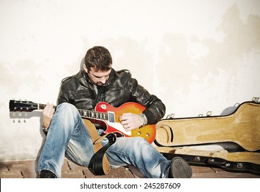 Guitar Player Against The Wall With An Open Guitar Case