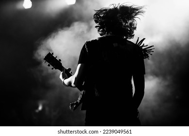 Un guitarrista haciendo rock durante un concierto. La banda de rock toca en el escenario. Guitarista juega solo.
