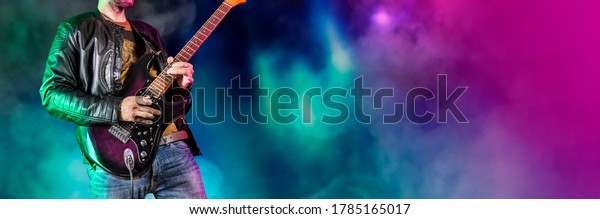 Guitar player performs on stage. Rock guitarist\
plays solo on an electric guitar. Artist and musician performs like\
rockstar. Black and white version. Green and pruple version.\
Panoramic image.