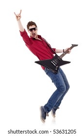 Guitar player playing his guitar on his tip toes and make a rock and roll sign