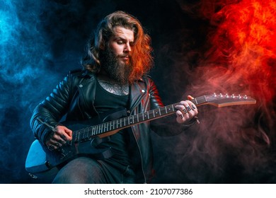 Guitar player. Rockstar bearded man with long hair plays on guitar isolated on smoke background. Studio shot 