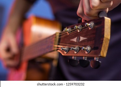 guitar player tweaking the guitar tuner of the fifth string on headstock, close-up - Shutterstock ID 1259703232
