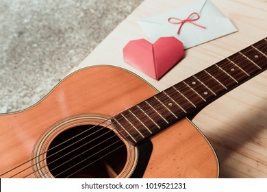 The guitar and red heart fold paper with white envelope. Long distance relationship and love song as a concept.