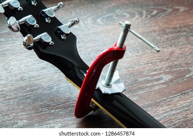 Guitar Repair. Broken And Cracked Guitar Neck Is Glued In And Tightened With A Clamp.