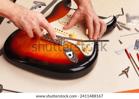 Guitar repairer sets the pickguard on electric guitar.