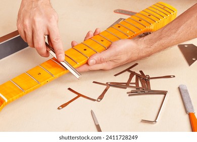 Guitar repairman crowning frets on the guitar neck with special fret files.
