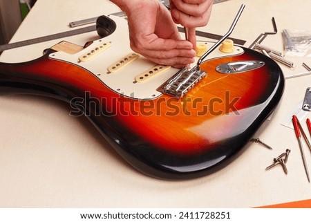 Guitar repairman sets the pickguard on electric guitar.