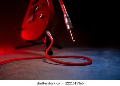 The guitar standing on the stage and one end of the jack cable connected to it are not plugged into the amp.