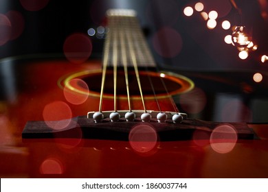 Guitar String holder and lower threshold of a six-string acoustic guitar close-up on a black background.