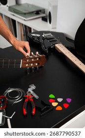 Guitar string replacement and tuning preparation. Musician tunes a guitar using tools and spare strings. Guitar tuning process includes adjusting pegs and preparing new strings for better sound