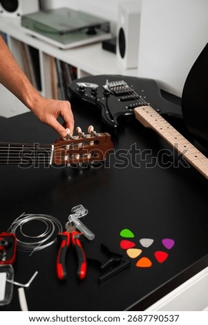 Guitar string replacement and tuning preparation. Musician tunes a guitar using tools and spare strings. Guitar tuning process includes adjusting pegs and preparing new strings for better sound