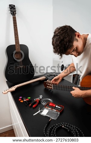 Guitar string replacement and tuning preparation. Musician tunes a guitar using tools and spare strings. Guitar tuning process includes adjusting pegs and preparing new strings for better sound