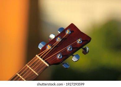 Guitar tuner. Wooden guitar on a natural blurred background. Guitar tuning. The guy tunes the guitar. - Shutterstock ID 1927293599