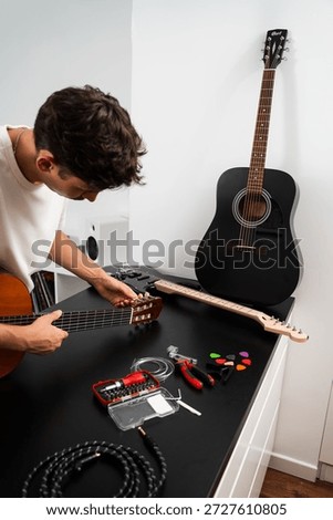 Guitar tuning process includes adjusting pegs and preparing new strings for better sound. Guitar string replacement and tuning preparation. Musician tunes a guitar using tools and spare strings