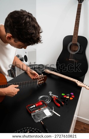 Guitar tuning process includes adjusting pegs and preparing new strings for better sound. Guitar string replacement and tuning preparation. Musician tunes a guitar using tools and spare strings