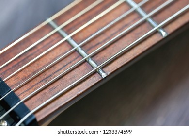 guitar  with wooden brown neck and strings, close up blurry background, texture, abstract