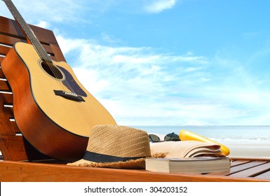 Guitar,hat,book and beach accessories on a beach chair with sea background
 - Powered by Shutterstock