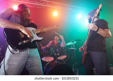 Guitarist and bass player perform on stage. Stage light, smoke.