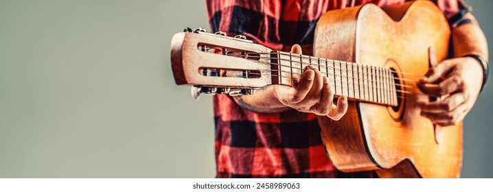 Guitarist, music.Young man plays an acoustic guitar on a gray isolated background. Man's hands playing acoustic guitar, close up. Acoustic guitars playing. - Powered by Shutterstock