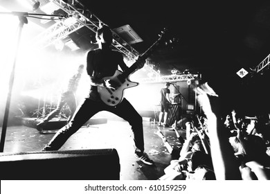Guitarist on a stage playing rock to the crowd of people. black and white