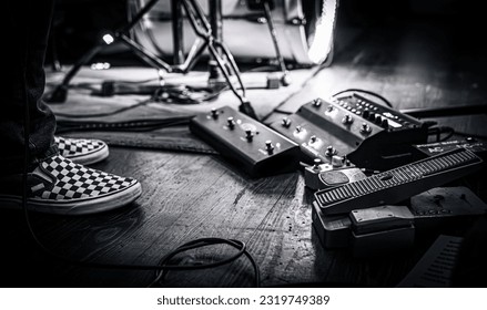 Guitarist pedalboard on a live concert stage next to his feet. Intimate classic rock gig. - Powered by Shutterstock